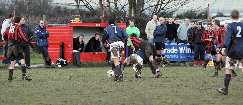 Jim Smith gets the ball away from Marc Cooper in front of the Wick bench

